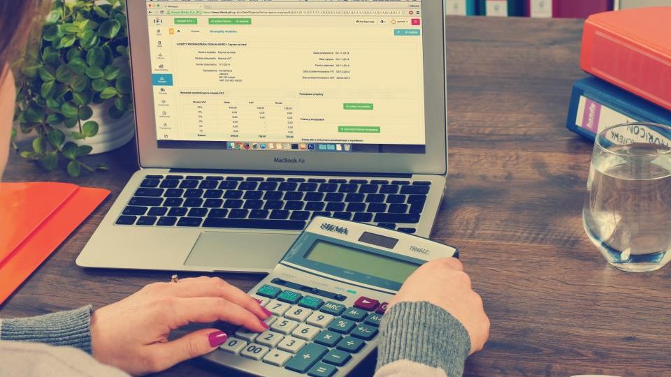 Un portatile con un foglio di calcolo e una calcolatrice su una scrivania